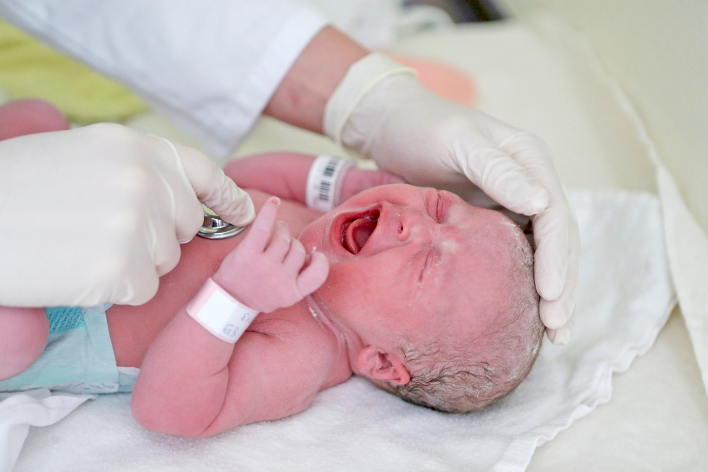 Die Hände eines Arztes bei der U1 eines Neugeborenen im Kreißsaal