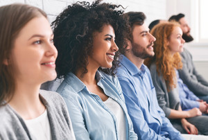 Junge Menschen verschiedener Nationalitäten sitzen in einer Reihe