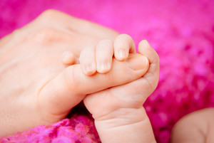 Der Finger eines Erwachsenen hält die Hand eines Babys
