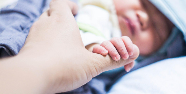 Die Hand eines Babys greift nach der eines Erwachsenen