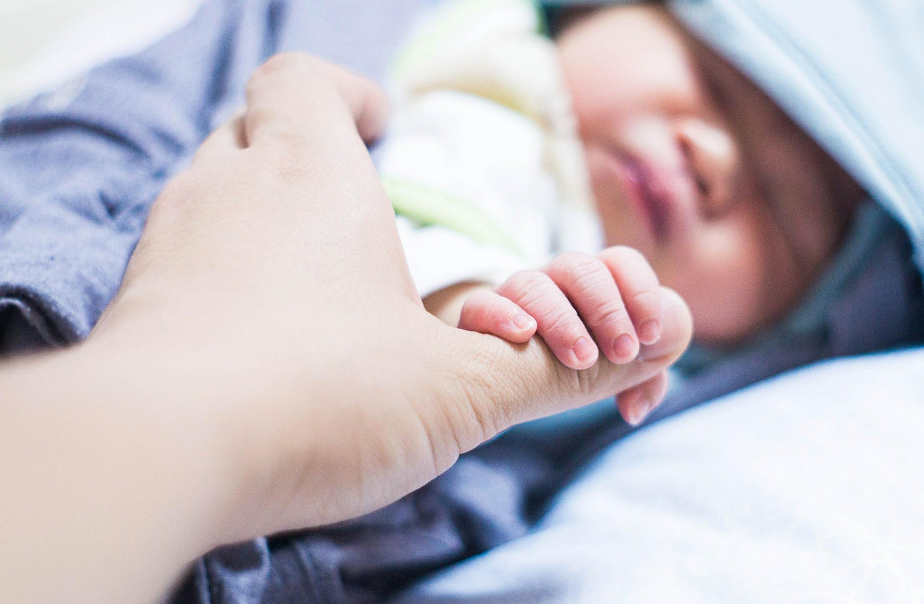 Die Hand eines Babys greift nach der eines Erwachsenen