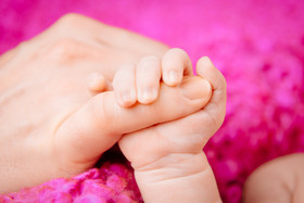 Der Finger eines Erwachsenen hält die Hand eines Babys