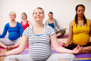 Eine Gruppe Schwangerer entspannt beim Yoga