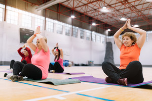 Eine Gruppe Damen sitzend beim Yoga in einer Turnhalle