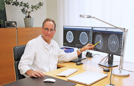 Schlaganfallexperte Prof. Dr. med. Thorsten Steiner, Chefarzt der Neurologie am varisano Klinikum Frankfurt Höchst, vor Monitoren mit Aufnahmen von Hirnblutungen.