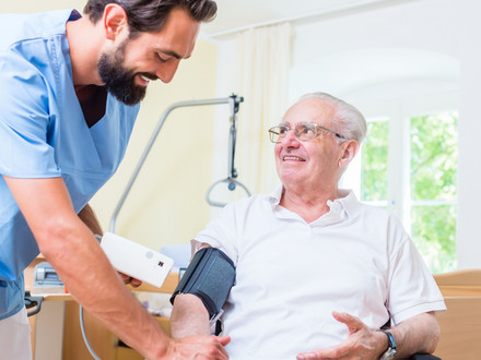 Älterer Patient mit Pfleger beim Blutdruck messen