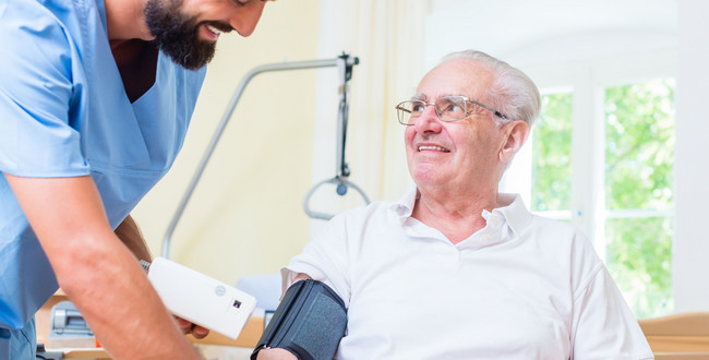 Älterer Patient mit Pfleger beim Blutdruck messen