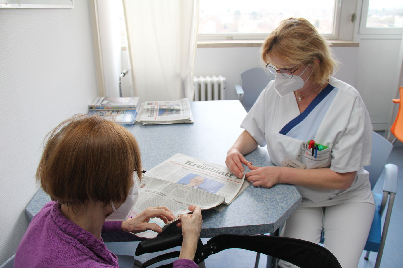 Ergotherapeutin Iris Hogelucht (r.i.B.) mit einer Patientin der Altersmedizin beim Zeitunglesen