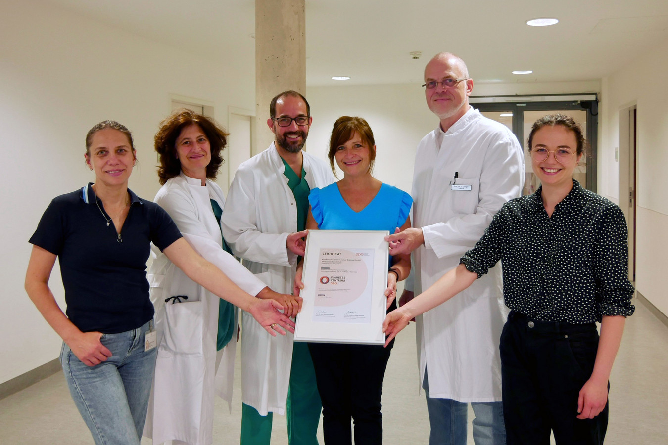 Die Mitarbeiter:innen des Diabetes-Teams halten gemeinsam das Zertifikat in die Kamera und lächeln.  i
