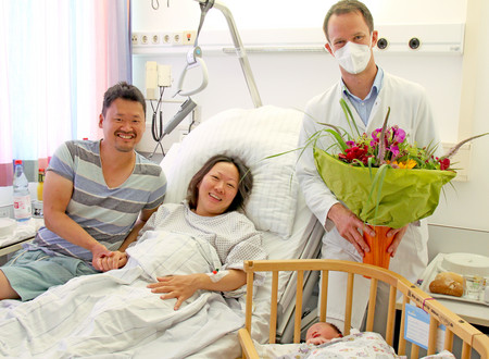 Der Chefarzt der Klinik für Gynäkologie und Geburtshilfe, Prof. Dr. med. Joachim Rom, überreicht den glücklichen Eltern der 1111 Geburt am varisano Klinikum Frankfurt Höchst einen Blumenstrauss.