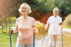 Eine ältere Dame und ein Herr beim Nordic Walking in der Natur