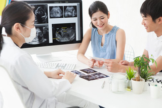 Eine Ärztin berät ein junges Paar zur Schwangerschaft