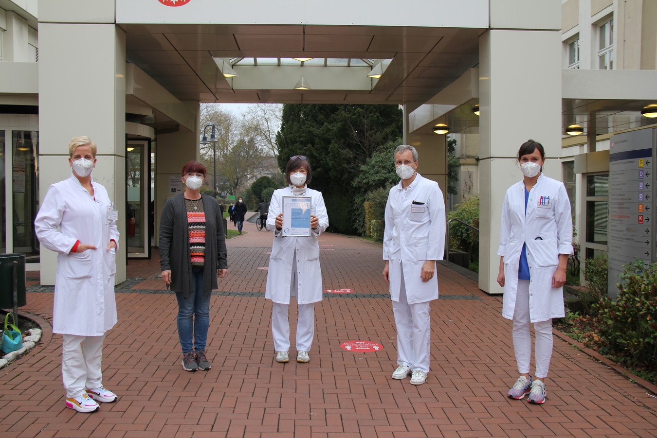 Gruppenbild der an der Rezertifizierung des AltersTraumaZentrums beteiligten Kolleg:innen vorm Haupteingang der Klinik