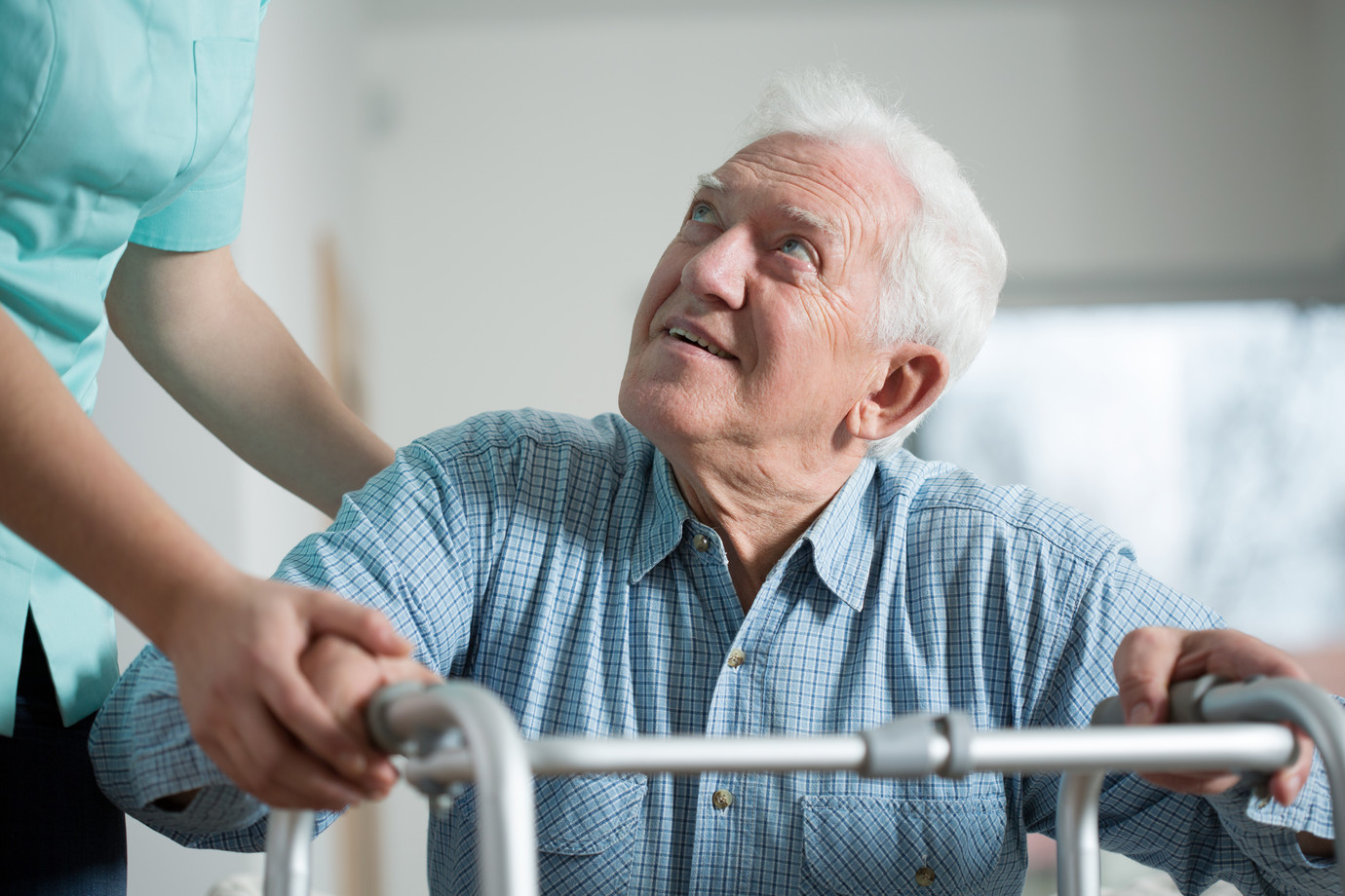 Pflegekraft hilft älterem Herren beim Aufstehen