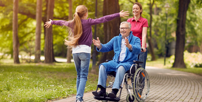Ein Großvater im Rollstuhl wird von seiner Enkelin empfangen